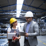 Manager supervisor and worker discussing about production results and new strategy in factory industrial hall.